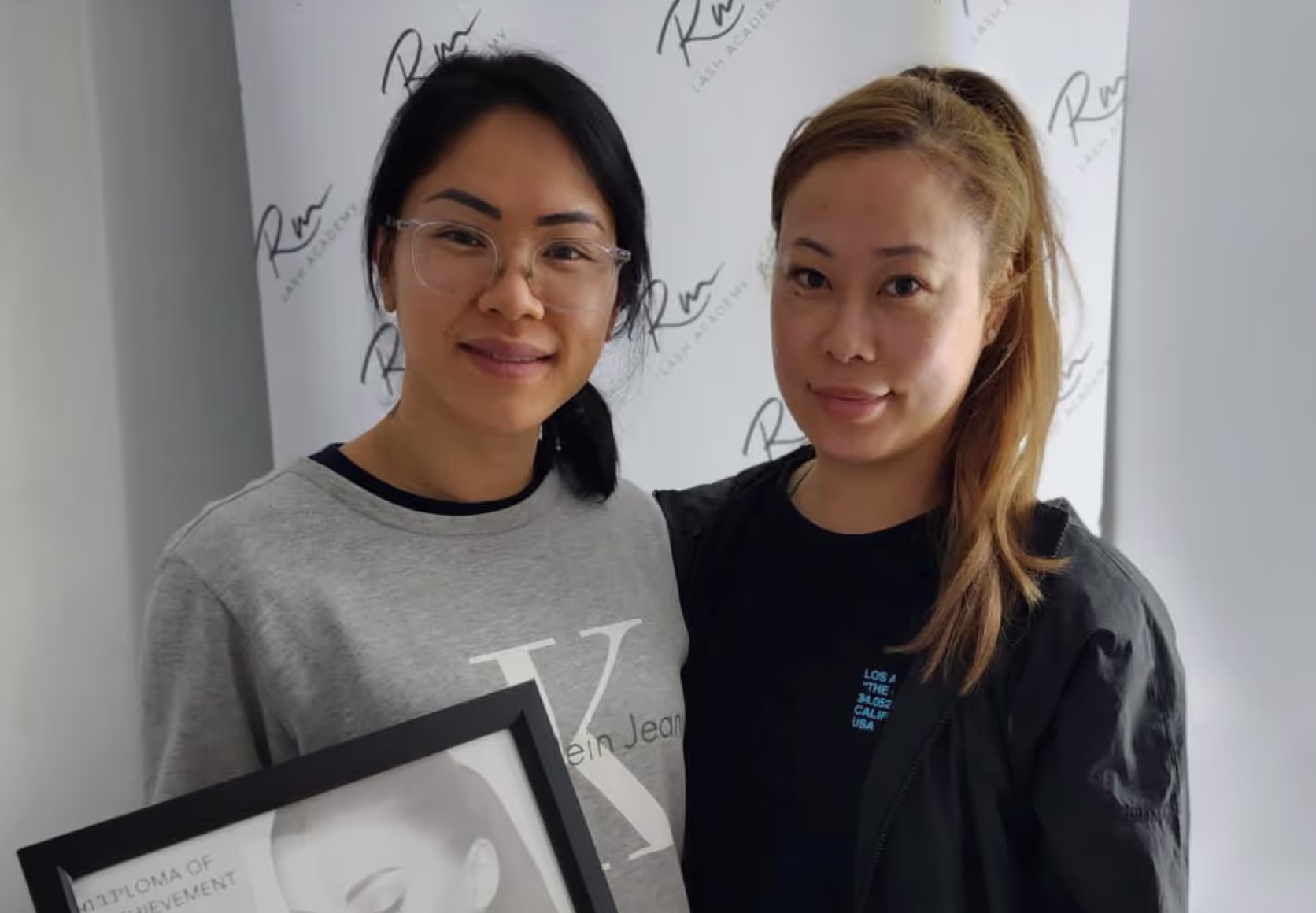 Two lash students holding a certificate.