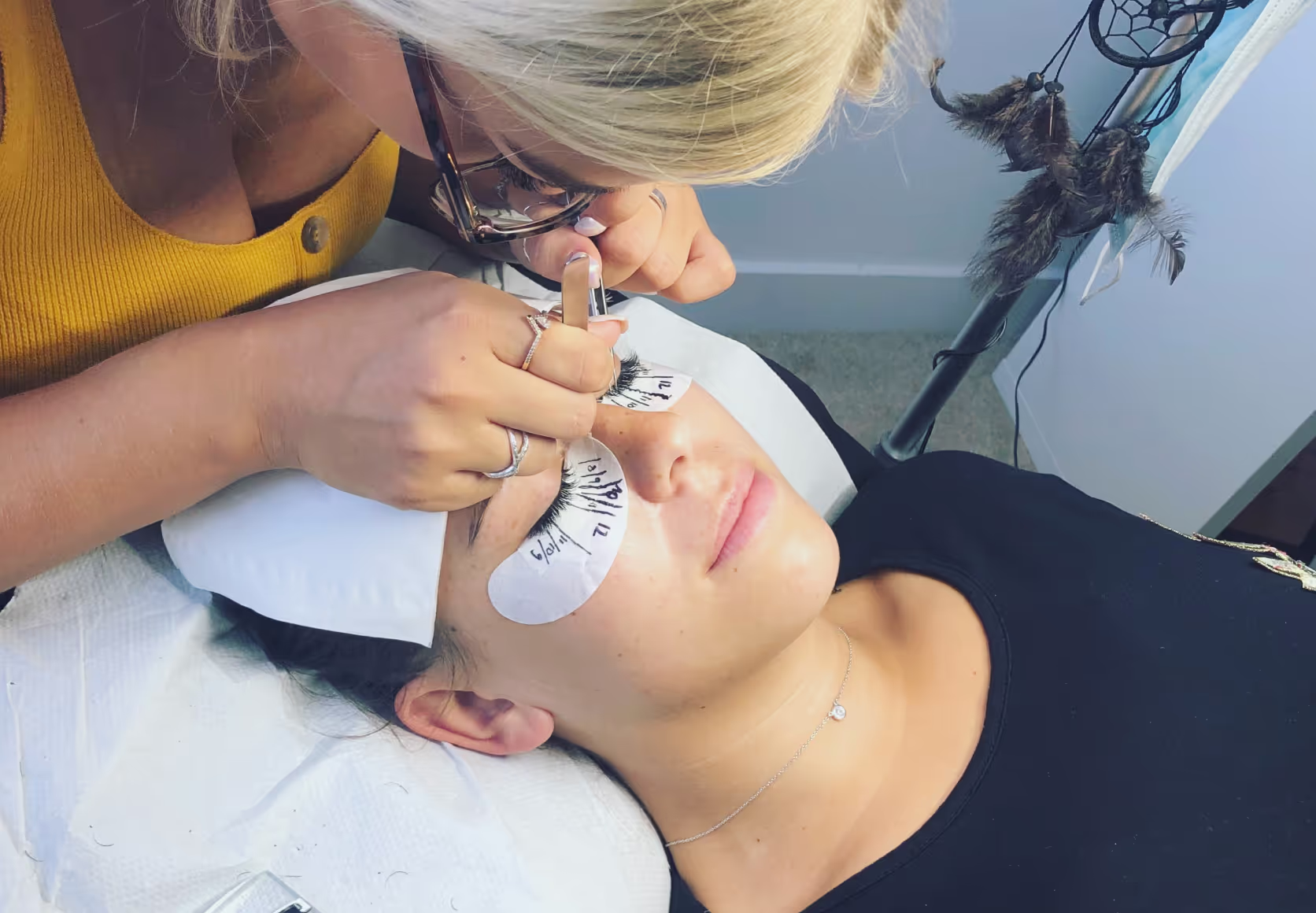 Student applying lashes on a model during training.