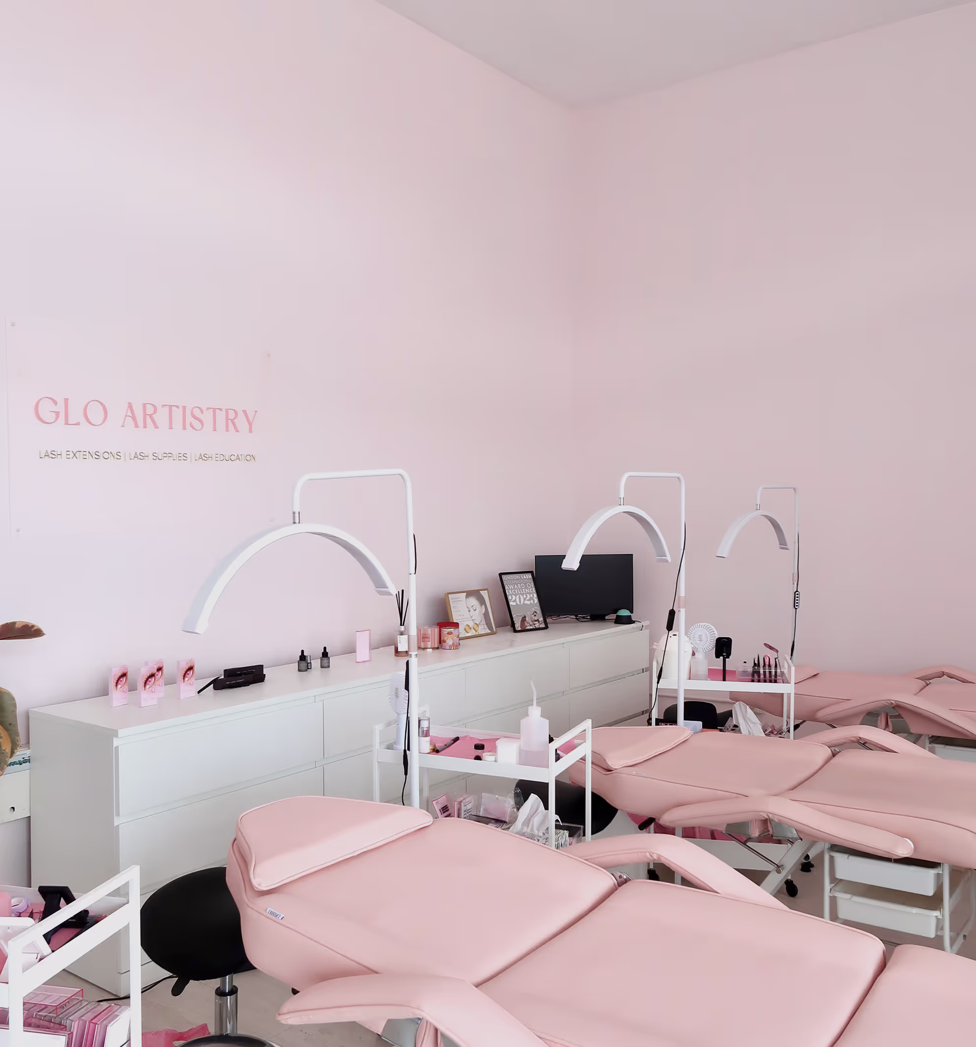 GLO Artistry lash studio interior with pink aesthetic, lash beds and professional lash extension setup in a clean, modern environment.