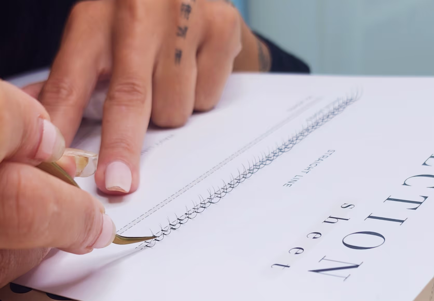 Student applying lashes on practice sheets during lash training.