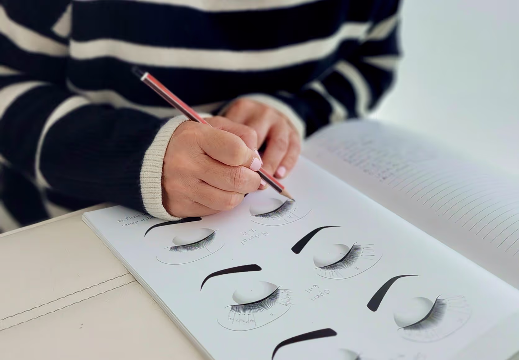 Student practicing lash styles on paper using practice sheets.
