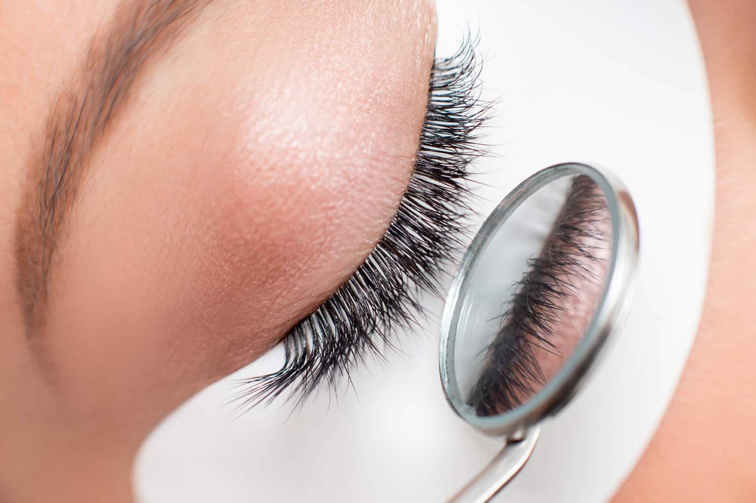 Close-up of eyelash extensions applied in a voluminous style, with a magnifying tool highlighting the detail of the lashes, representing the Kardashian eyelash extensions look.