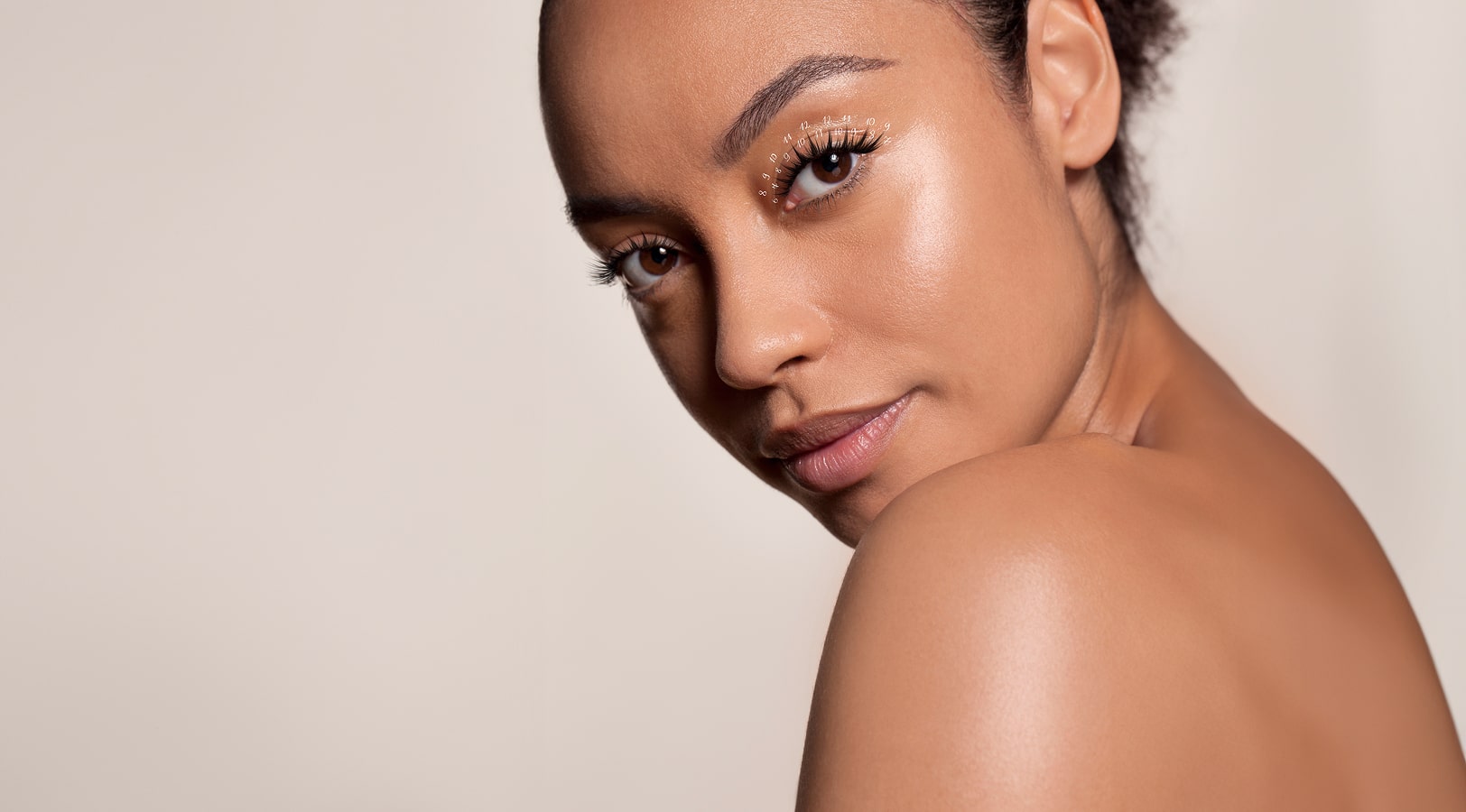 Close-up of a woman with glowing skin and perfectly styled wispy lashes, showcasing a natural, textured lash look.