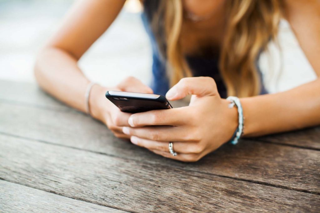 Girl uses mobile phone to find information about Instagram for her business.